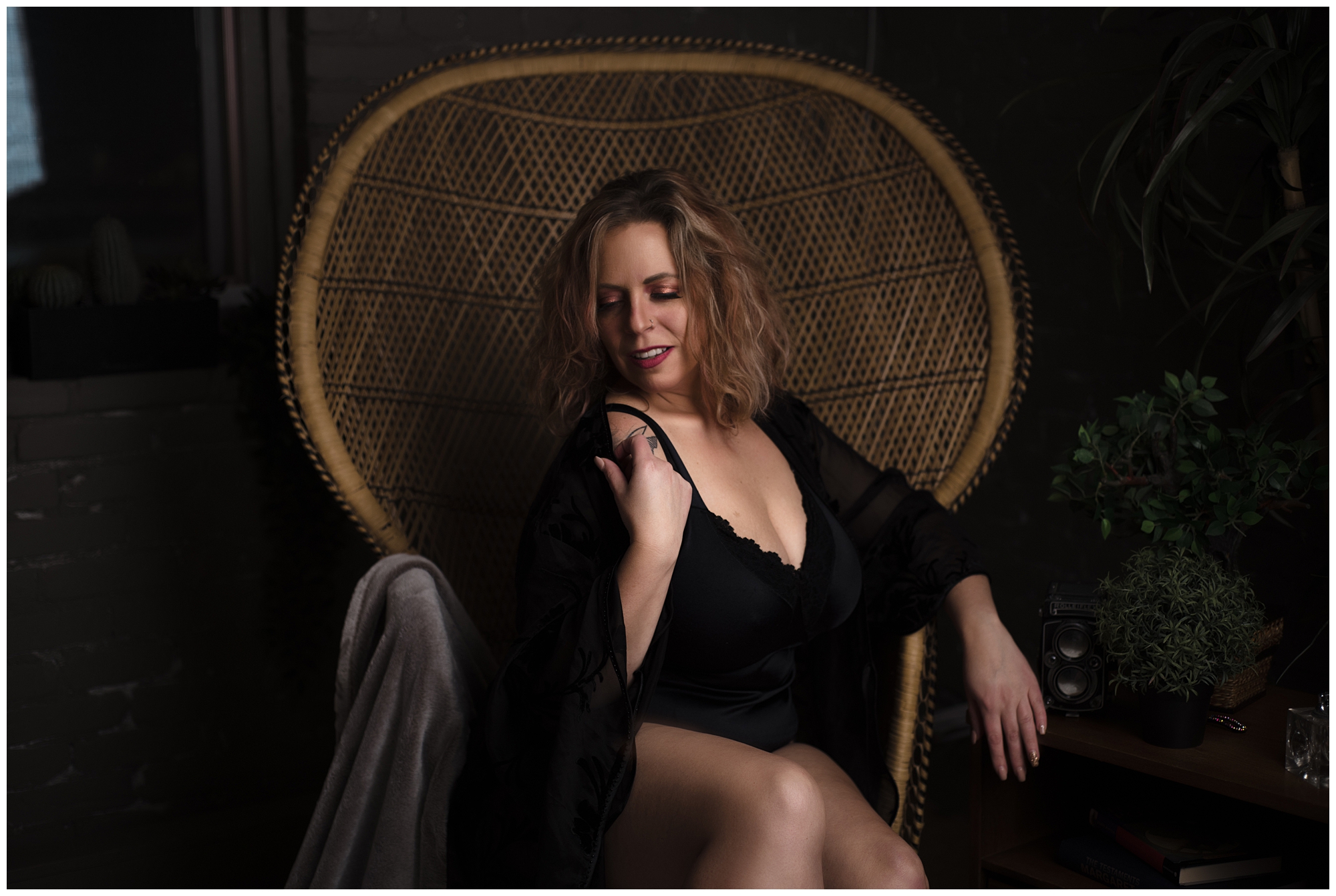woman in black lingerie posing in a peacock chair in a regina boudoir studio