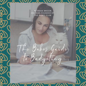 photograph of a woman wearing a white shirt, she is holding a white cat in one arm and with the other she is working on her babes guide to budgeting workbook